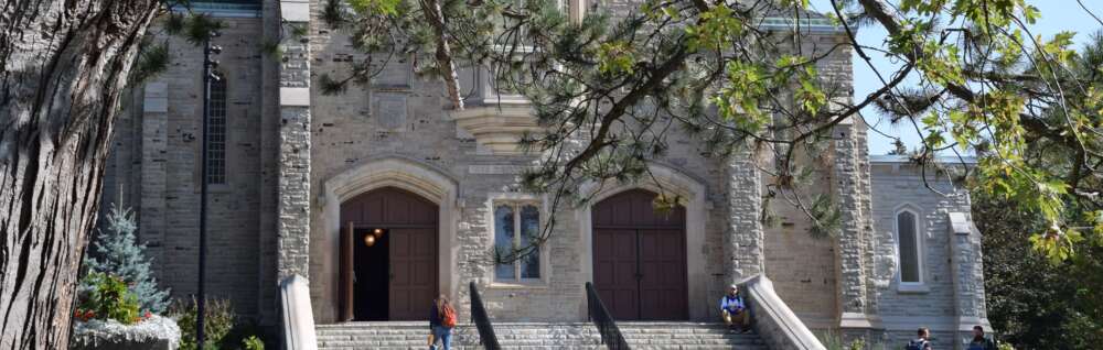 The stone War Memorial Hall with tree leaves in the foreground