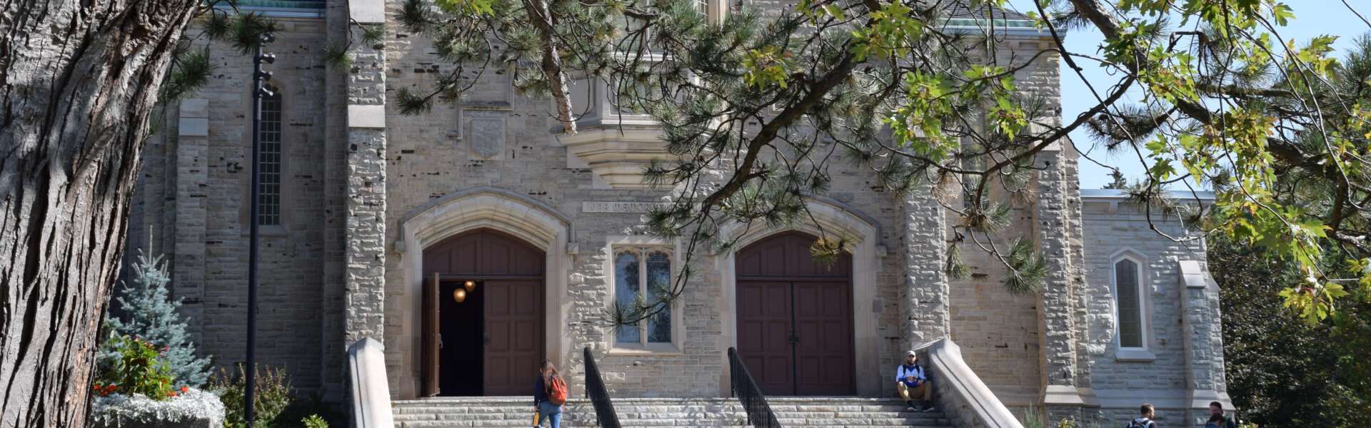 The stone War Memorial Hall with tree leaves in the foreground