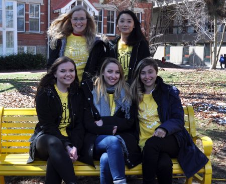 Students wearing yellow shirts sitting on Friendship Bench