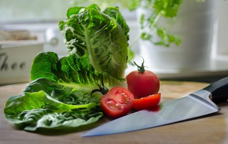 lettuce and a cut-up tomatoe sitting next to a knife