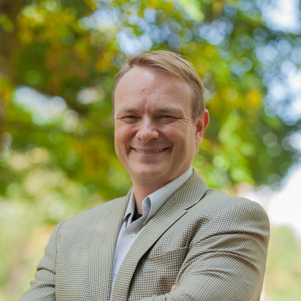 Dr. Evan Fraser headshot, standing outside with tree behind him