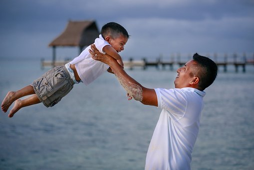 father lift his son up on the beach