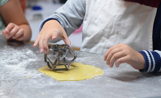 image of a child's hand pushing shaped cutters into dough