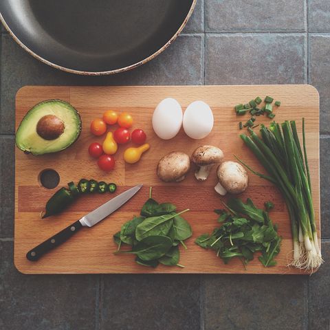 photo of vegetables, avocado, egg on a wooden cutting board with a knife