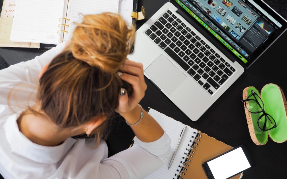 A photo of woman at a desk holding her head in her hand