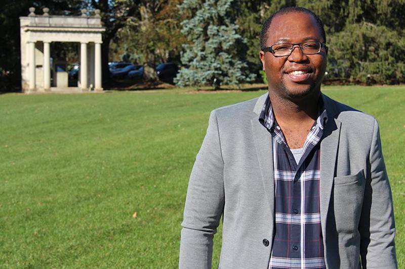 Professor in blazer standing in Johnston Green