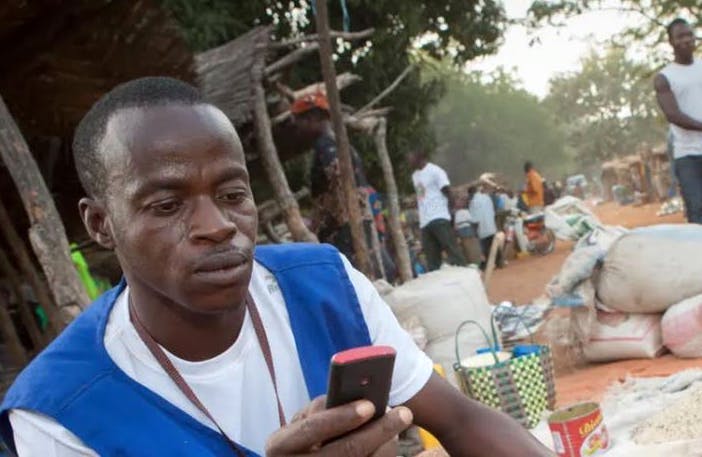 An African farmer is shown looking at a cellphone