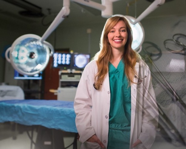 Dr. Michelle Oblak wears a lab coat and stands in a surgical ward