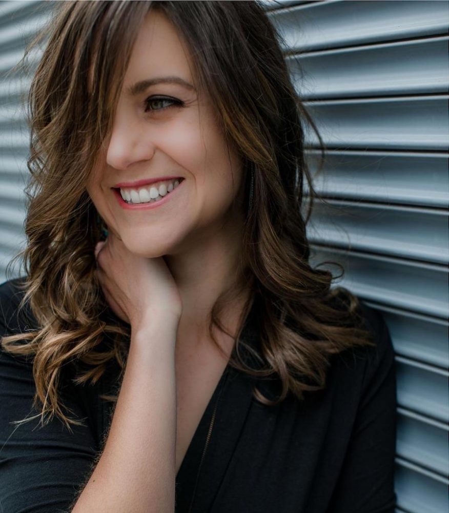 Dr. Brittany Luby leaning against a grey wall