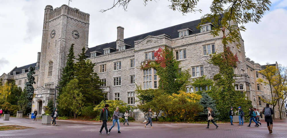 Students walk by Johnston Hall on a partly-cloudy day.