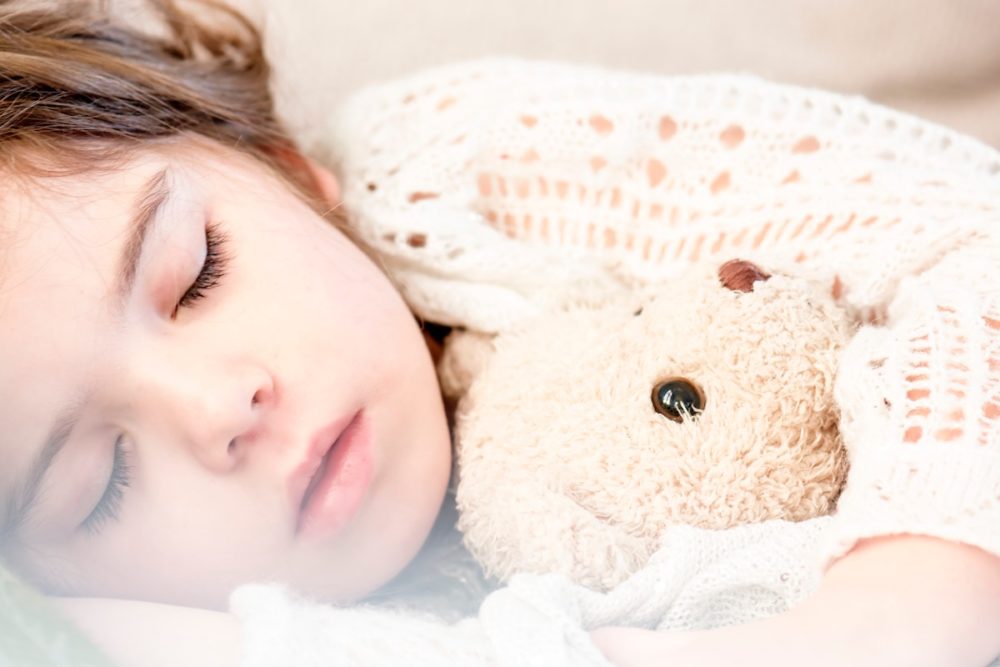 A preschool child sleeps with a stuffed toy
