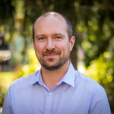Dr. Ryan Broll poses for a headshot in an outdoor setting.