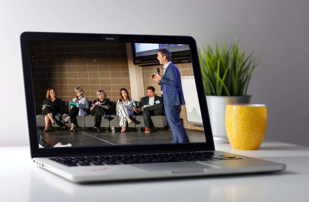 A laptop showing a speaker before a panel of judges on screen
