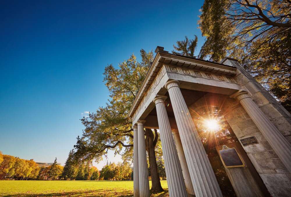 The sun shines through the U of G Portico as it sets.