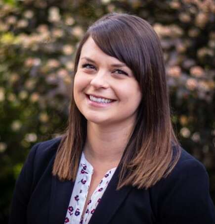 Dr. Kate Puddister smiles for a portrait in an outdoor setting.