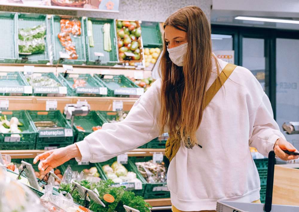 A woman wearing a mask shops for produce in a grocery store
