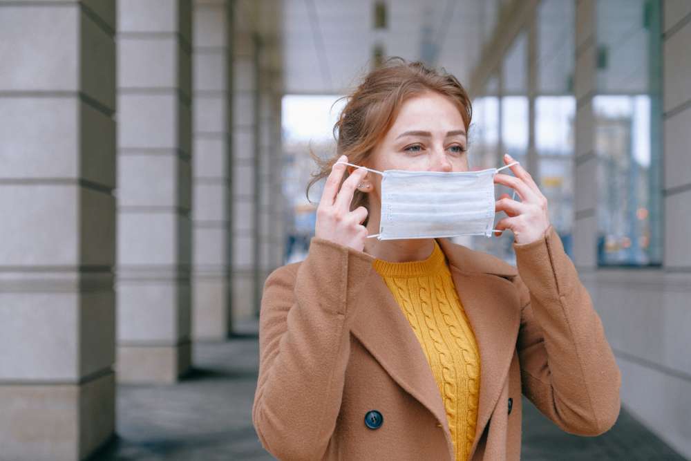 A woman puts on a face mask