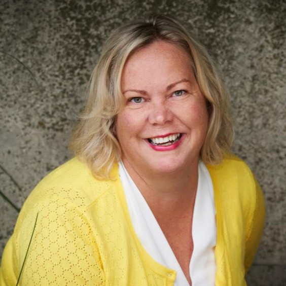 Dr. Helen Hambly poses for a headshot against a grey wall.