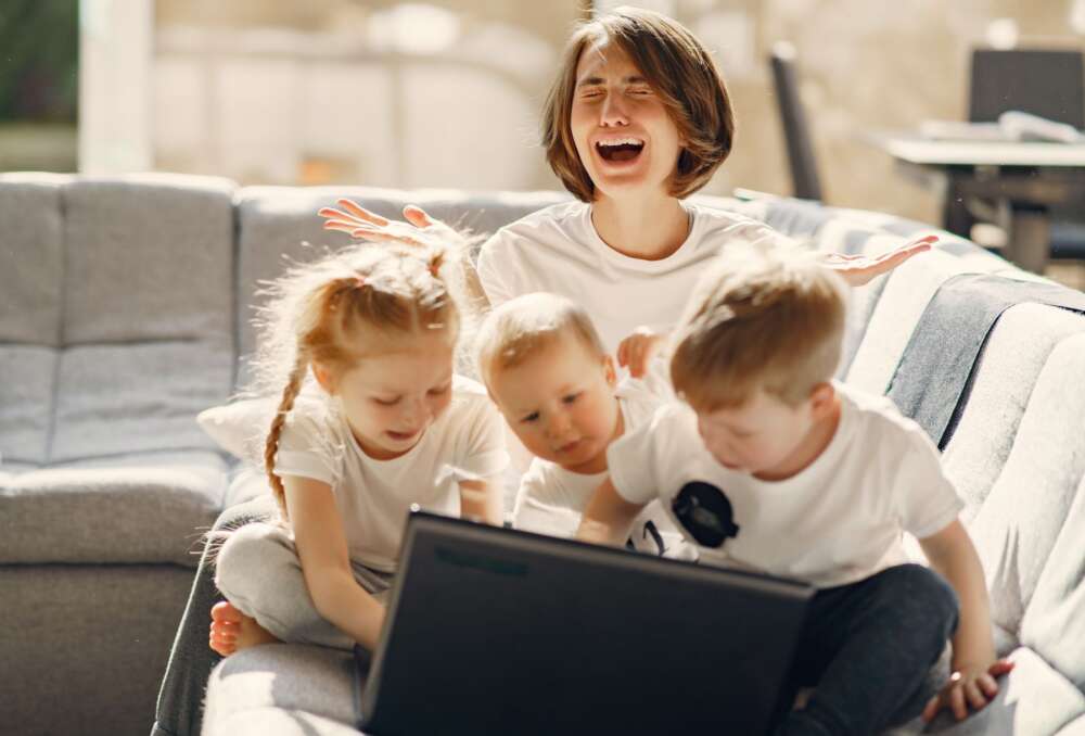 A mother is frustrated as 3 small children use her laptop.