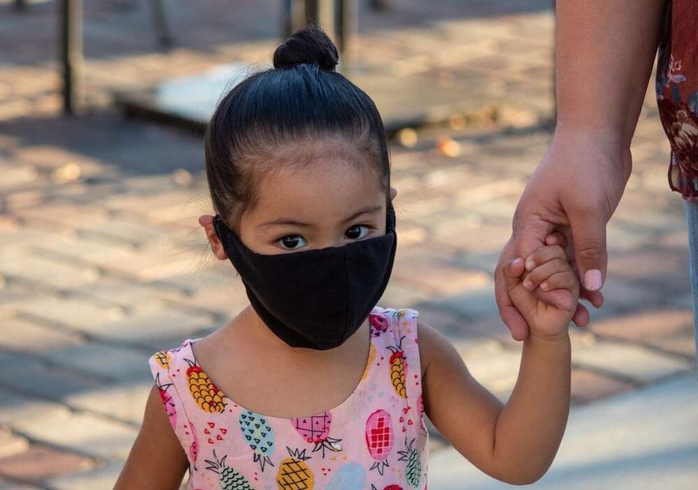 A preschooler wears a black surgical mask