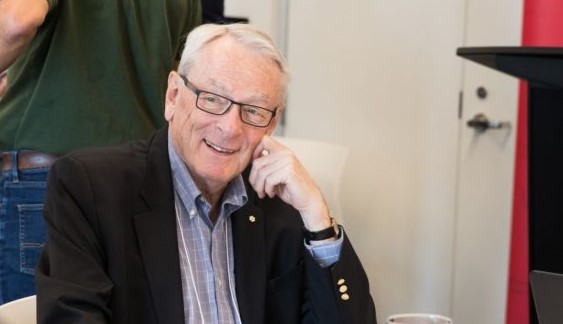 Dick Pound smiles while sitting at a table during a luncheon