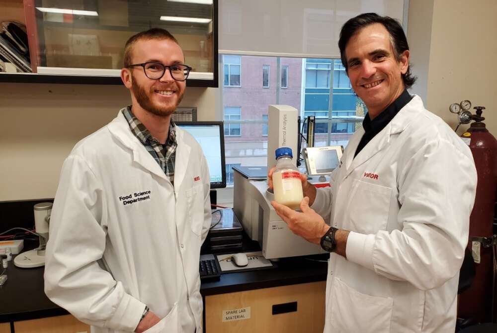 Prof. Alejandro Marangoni and PhD student Reed Nicholson wear lab coats and hold a bottle of liquid fat