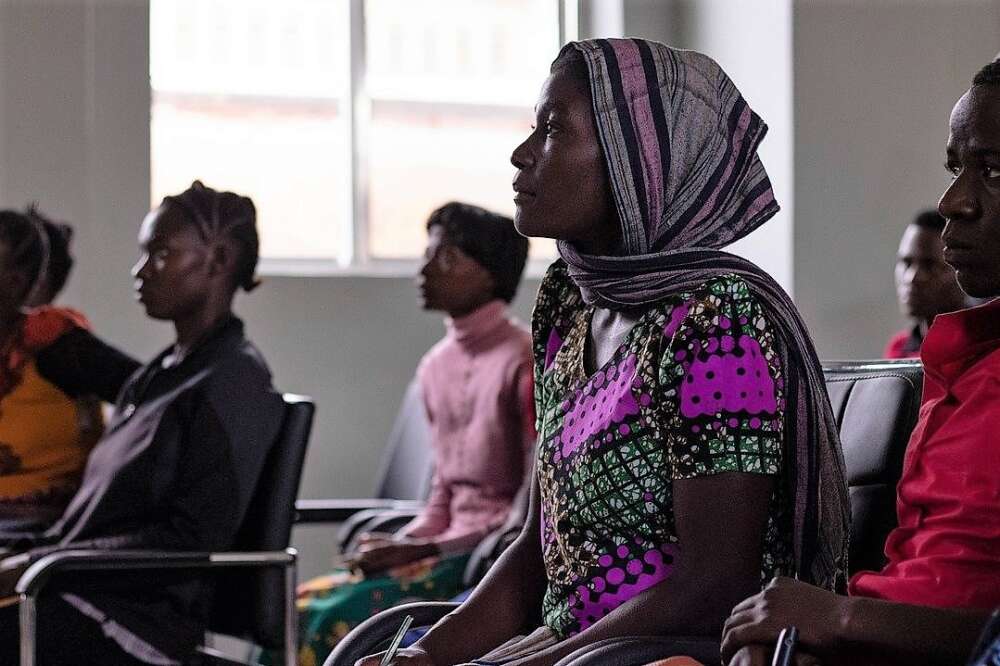 Women sit in rows of chairs listening to someone speak