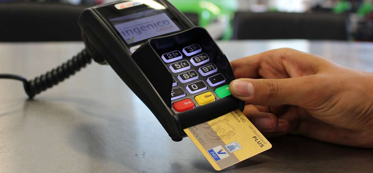 A hand inserts a credit card into a payment terminal