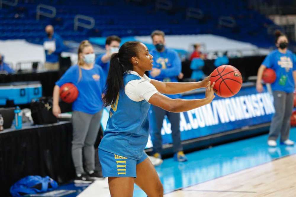 A player with the UCLA Bruins Women's basketball team. holds a ball and prepares to take a shot.