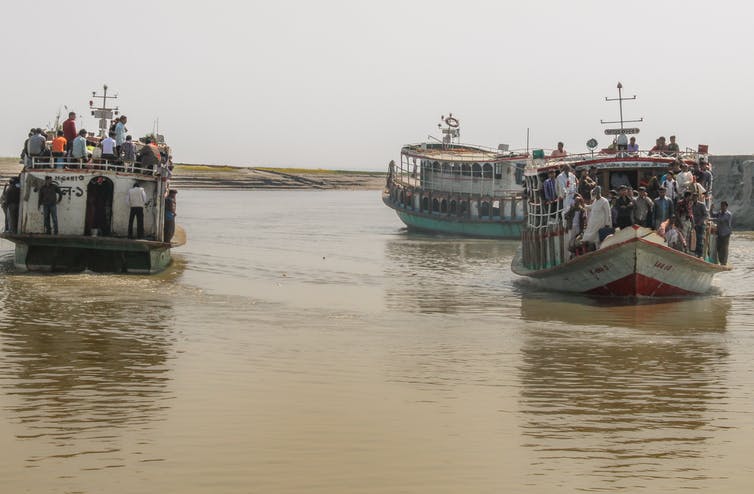 lartge boats on murkey brown water filled with people migrating because of floods