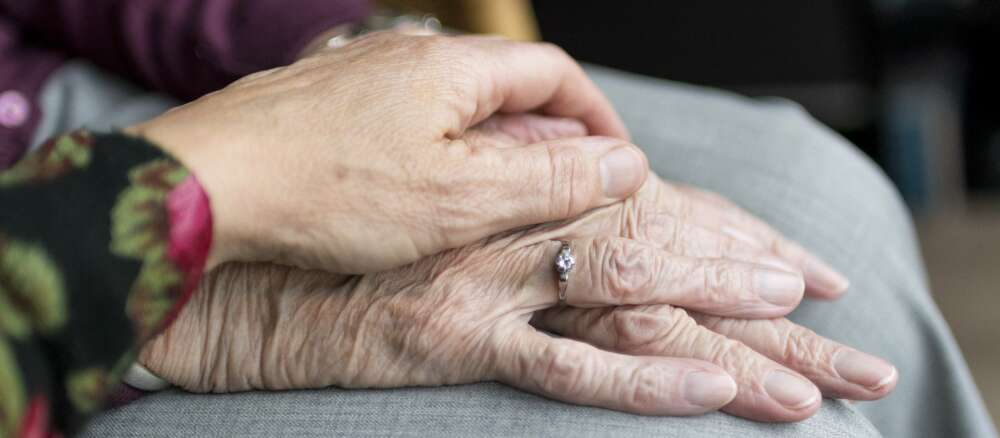 A senior puts their hand onto the hands of another senior