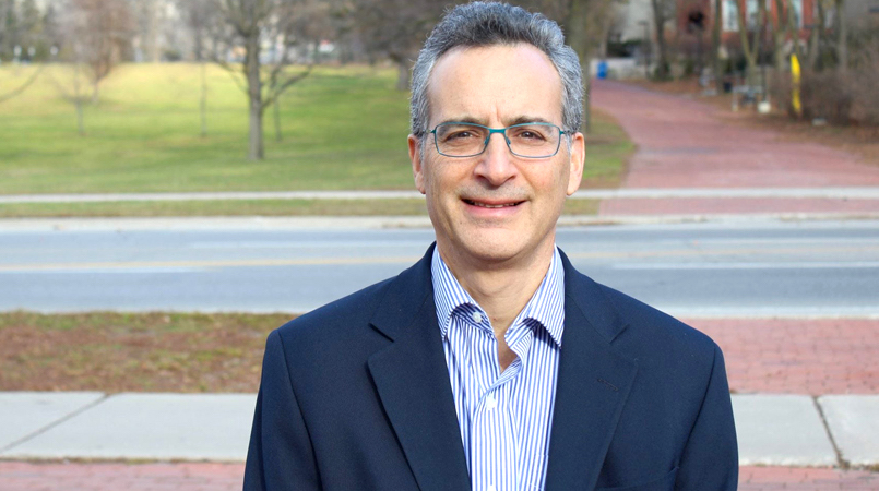 Dr. Jeff Farber smiles while posing for a photo near a road
