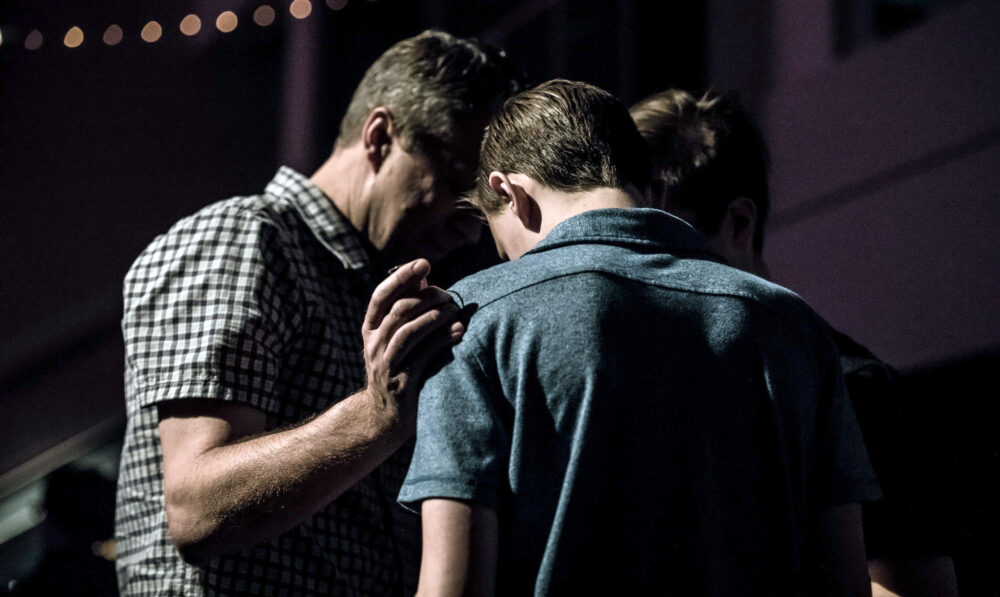 Three people put heads together to hug