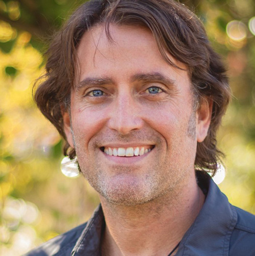 Dr. Philip Loring poses for a headshot in front of a tree with yellow leaves.