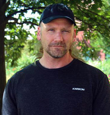 Dr. Thomas Graham stands in front of trees and a field.