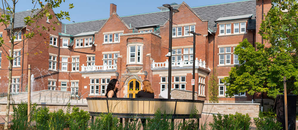 Two people sit at a curved bench in the Lang Plaza