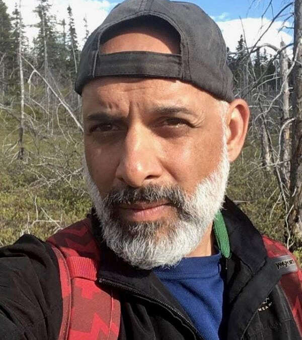 Dr. Faisal Moola in front of a wooded area.