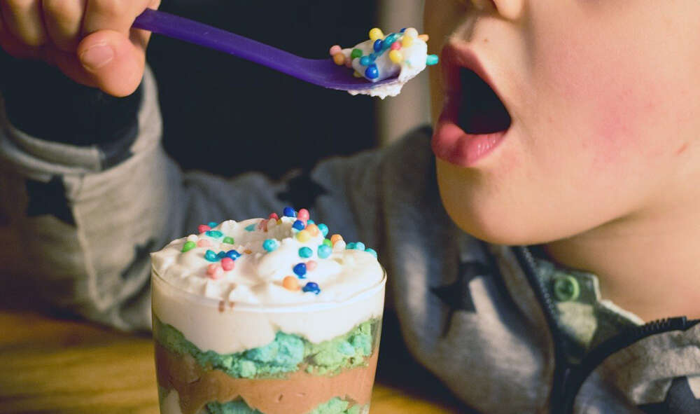 A child takes a spoonful of a sundae