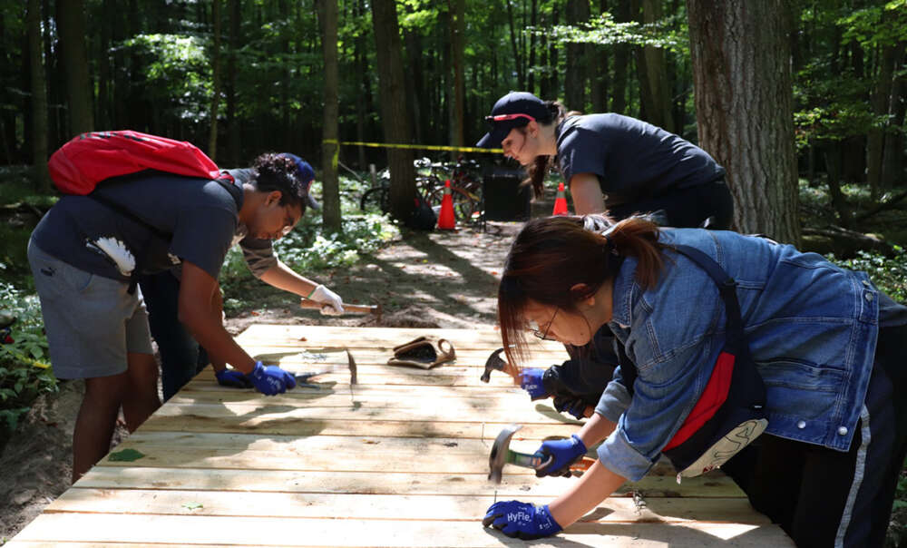 Three Project Serve volunteers hammer nails into boardwalks