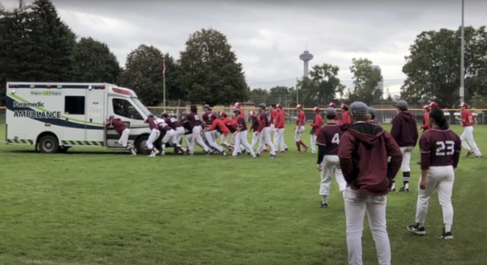 Gryphons and Marauders players help push an ambulance out of the mud