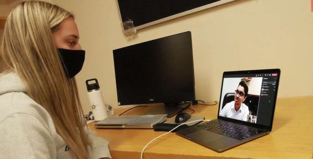 Young woman speaks with young man through laptop call.