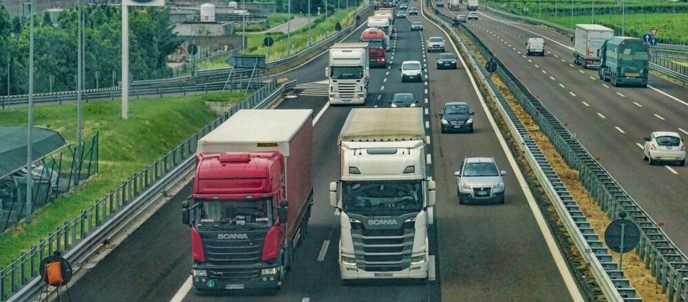 Several tractor trailers are seen on a highway from overhead