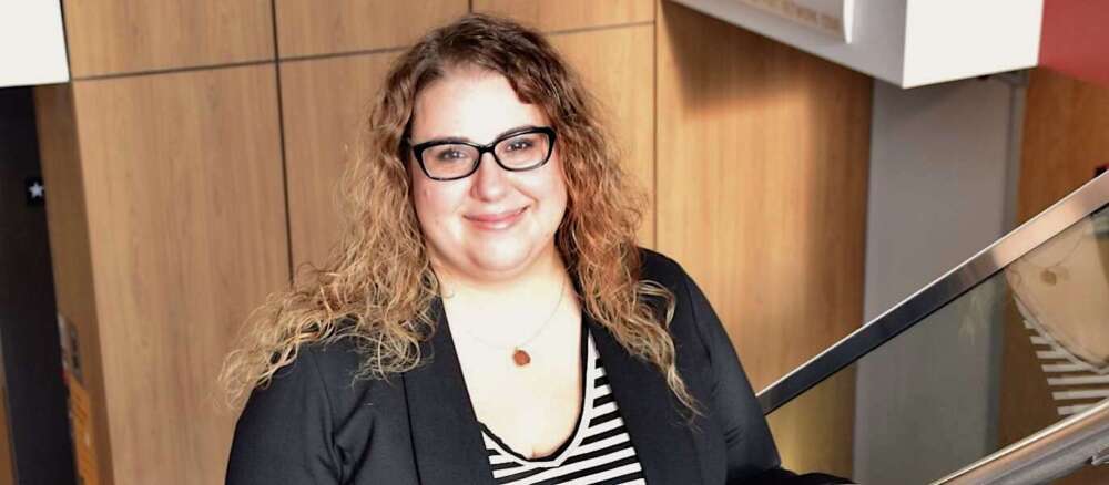 Woman with wavy hair and glasses smiles for camera