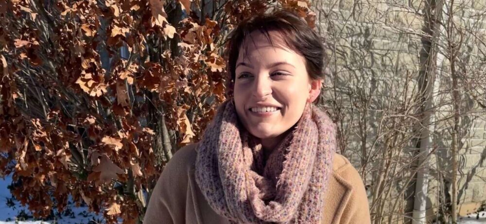 Emma Hak-Kovacs stands amid snow and smiles looking off-camera