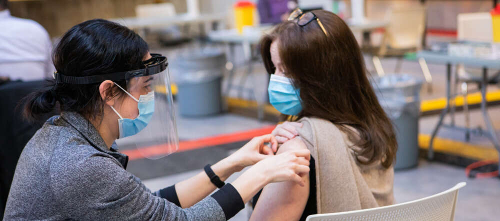 A person receives a COVID-19 vaccination from a health care worker