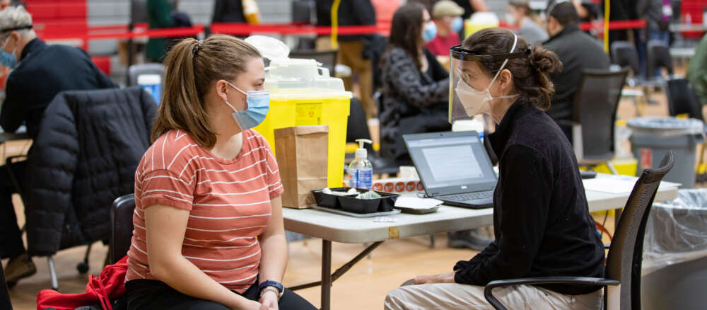 Two people sit at a table in the U of G vaccination centre on campus