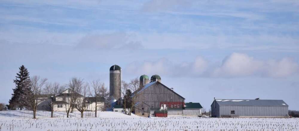A wide shot of a farm and field in winter