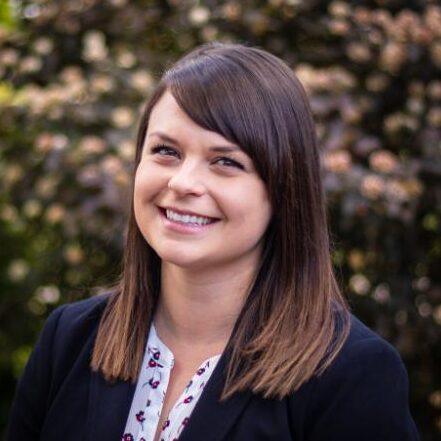 Dr. Kate Puddister smiles for a portrait in an outdoor setting.