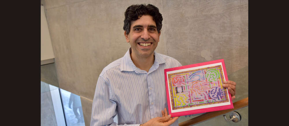 David Marom holds one of his 3-D mazes against a grey backdrop