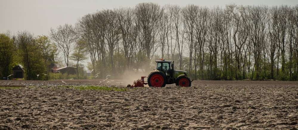 green and orange tractor on brown field during daytime
